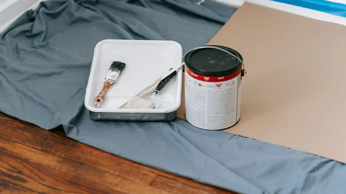 Paint can, tray, and brush set out on a drop cloth