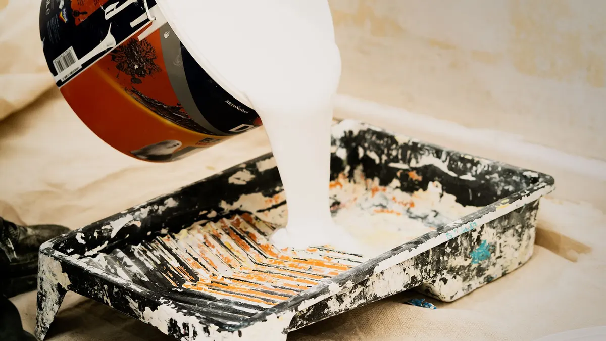 Paint can being poured into a tray for application
