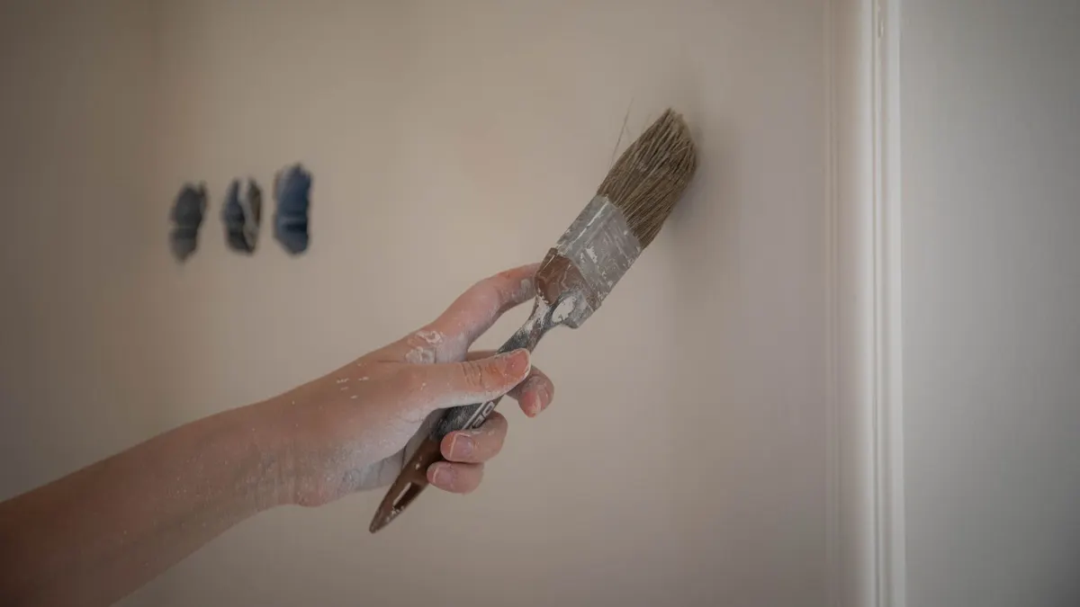 Paint brush touching up a small patch on a wall