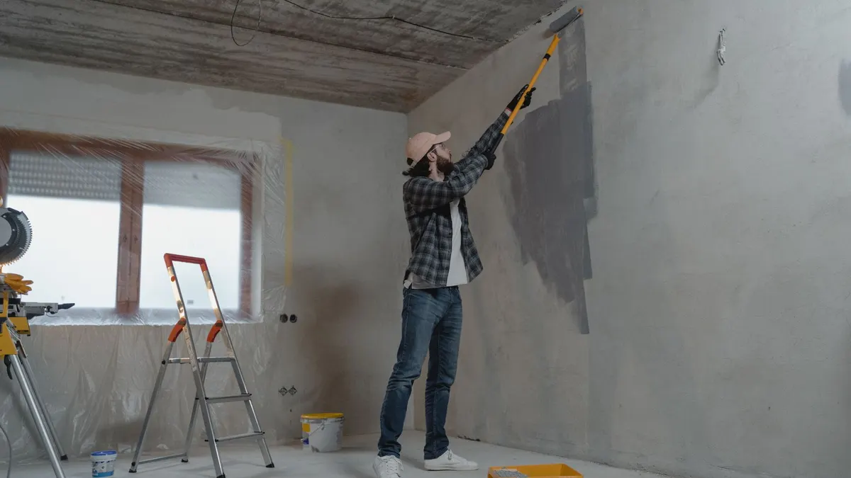 Person painting a ceiling with a roller on an extension pole
