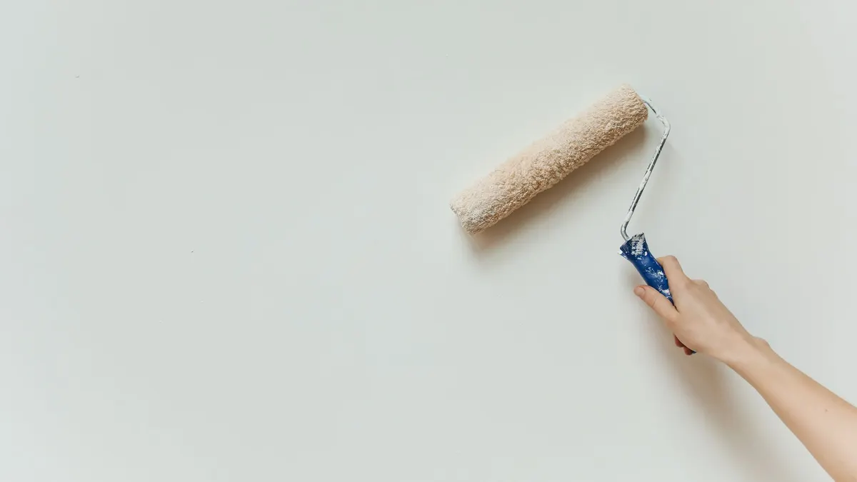 Close-up of a paint roller applying a fresh white coat to a wall