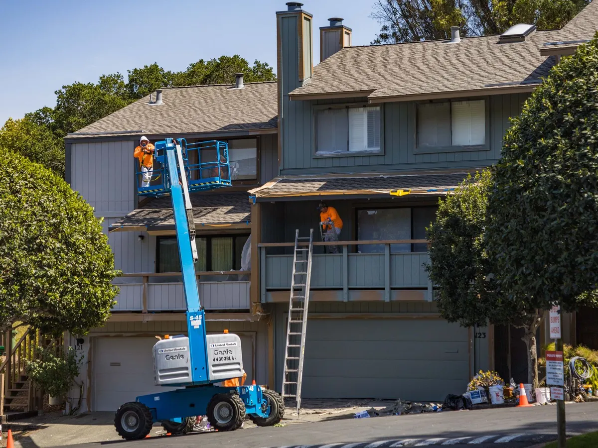 Painting crew on a lift working on a suburban house exterior