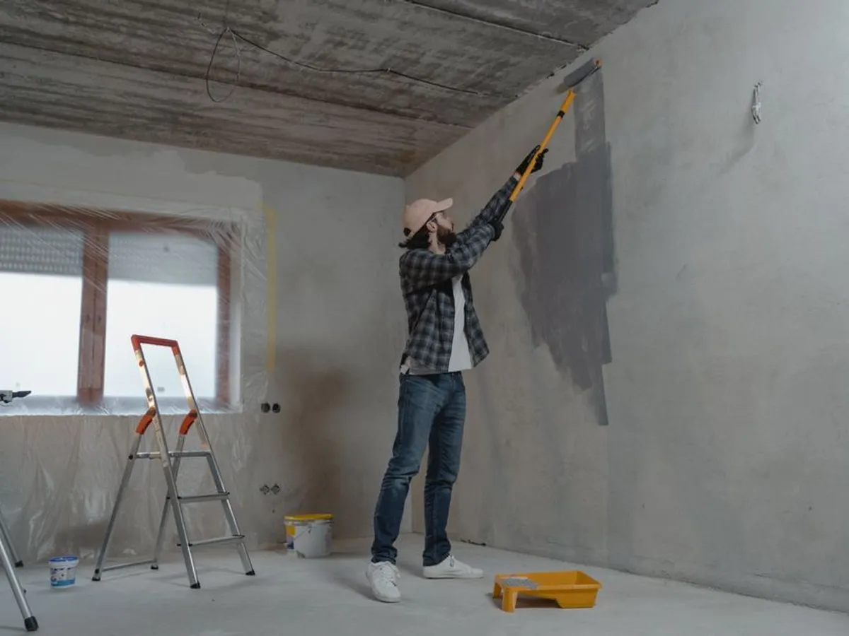 Painter rolling gray paint onto an interior wall